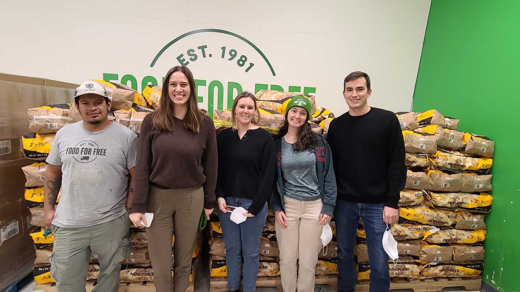Photo of recently promoted staff members posing in front of stacks of potatoes, with Food For Free logo partially visible on the wall behind.